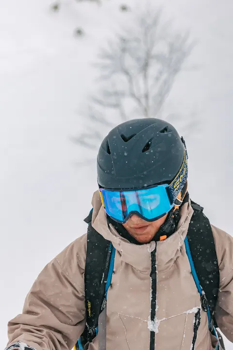 Smiling skier with goggles in falling snow