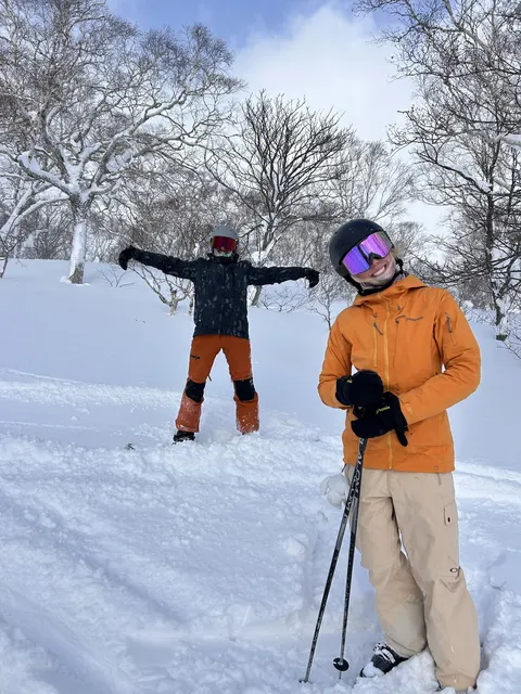 Two friends with arms out on a sunny slope