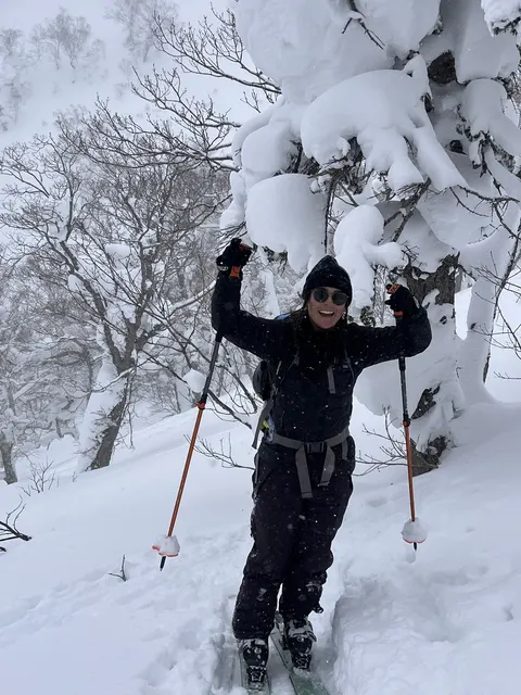 Skier with arms up below snowy trees
