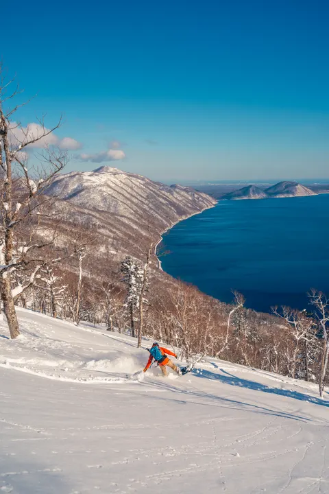 Skier turning through powder above a lake