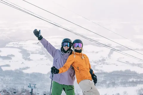 Two friends waving at the top of the gondola