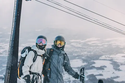 Two friends at the top of a lift above the valley