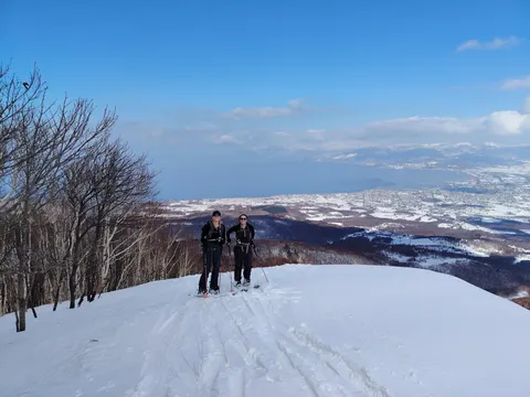 Two skiers on a summit above the sea