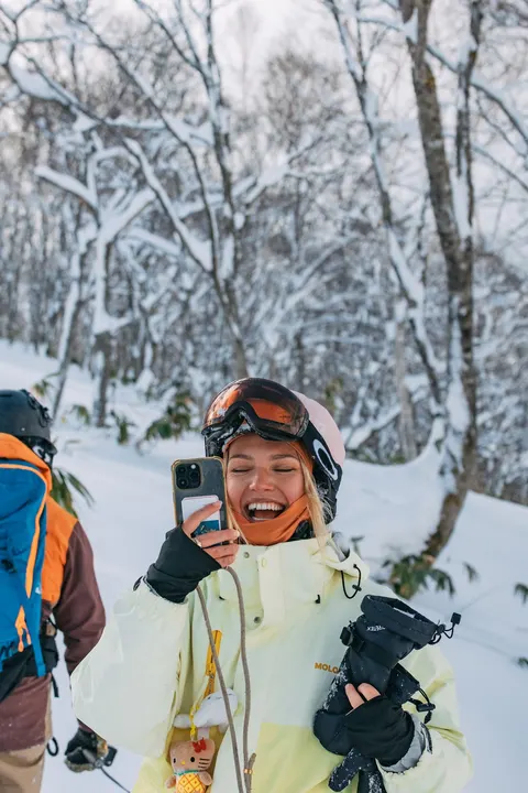 Laughing skier in a yellow jacket in the trees