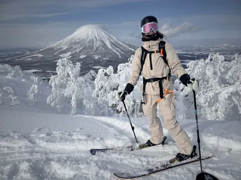 Skier between snow-covered trees with Mt Yotei behind