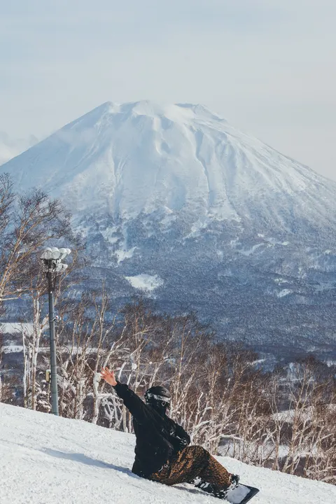 Snowboarder sitting in the snow below Mt Yotei