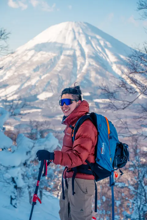 Ski tourer in a red jacket with Mt Yotei behind