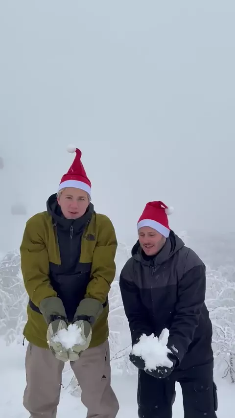 Two housemates in Santa hats having a snowball fight